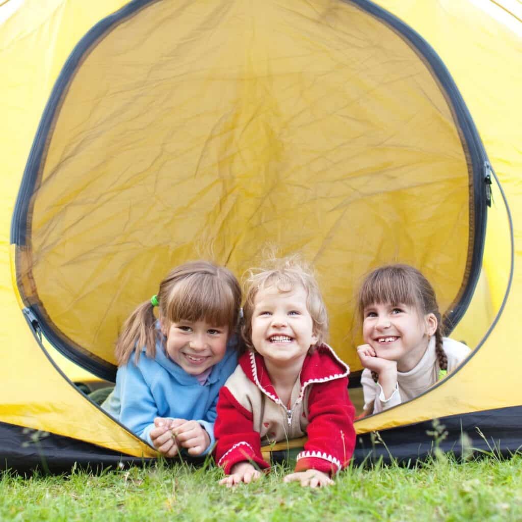 three young children in the doorway of a yellow tent