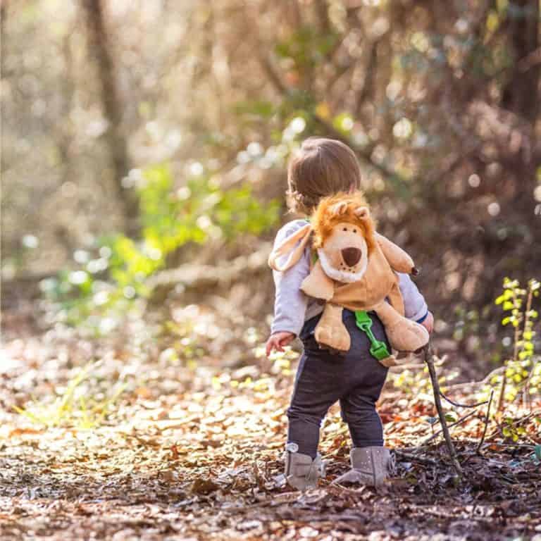 toddler hiking in the forest wearing a lion backpack