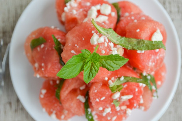 A plate of watermelon chunks with chiffonade mint and feta cheese