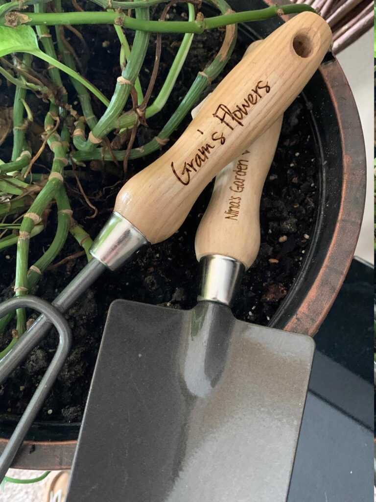 a close up of the wood handles of a pair of garden tools engraved with "gran's flowers"