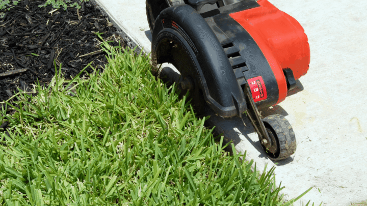 Text reads 'Best electric lawn edgers to make edging quick and easy' in a white transparent text box above the photo. The photo is of an electric edger with two wheels, a red cover, and a black shroud. Edger is on a sidewalk edging a grassy patch.