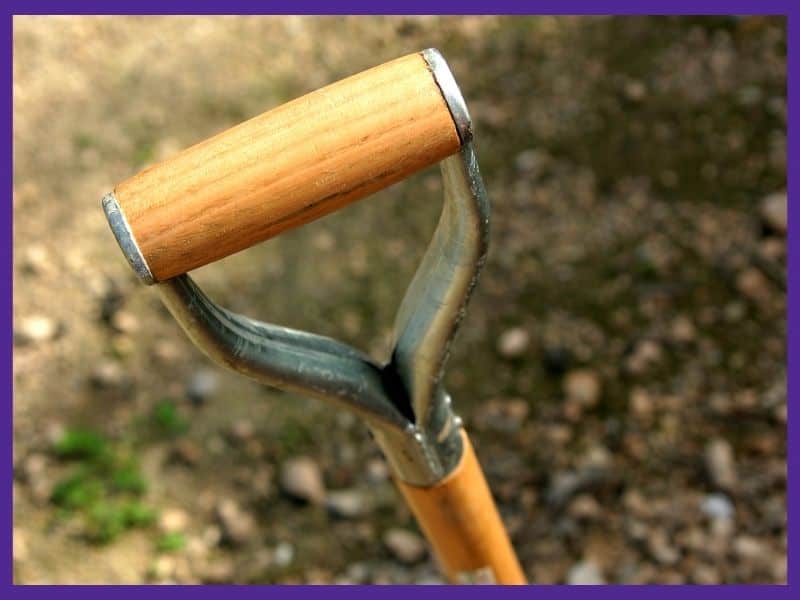 A close up of a metal and wood spade handle with a D shaped end