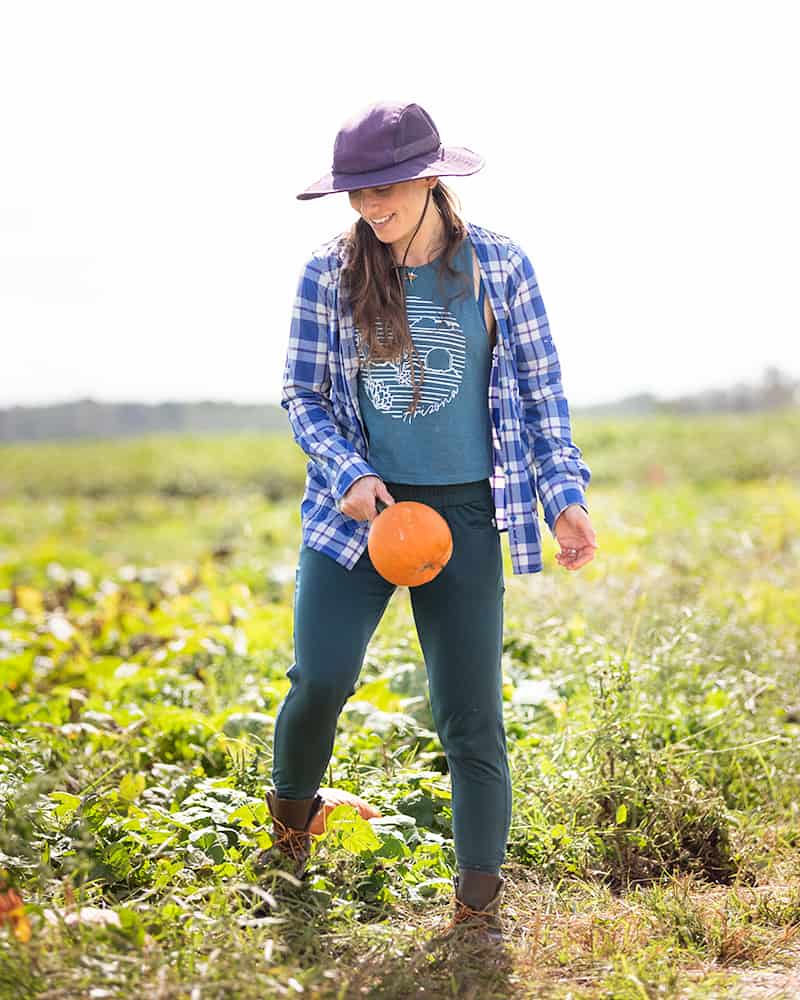 A woman in a pumpkin patch holding a small pie pumpkin