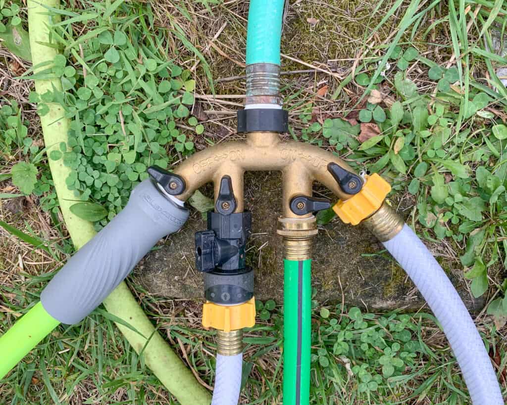 A brass four way hose splitter with a hose attached to every outlet