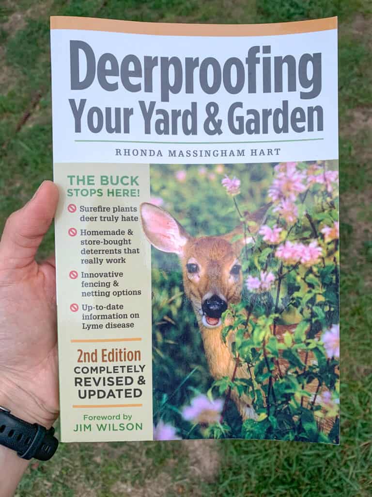 A hand holding the book "deerproofing your yard and garden"