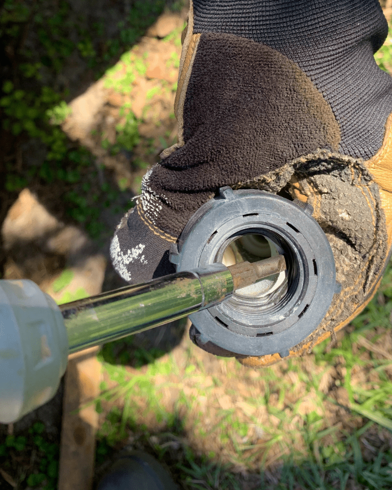 Photo is of a person prying out a hose washer with a flat head screwdriver. 