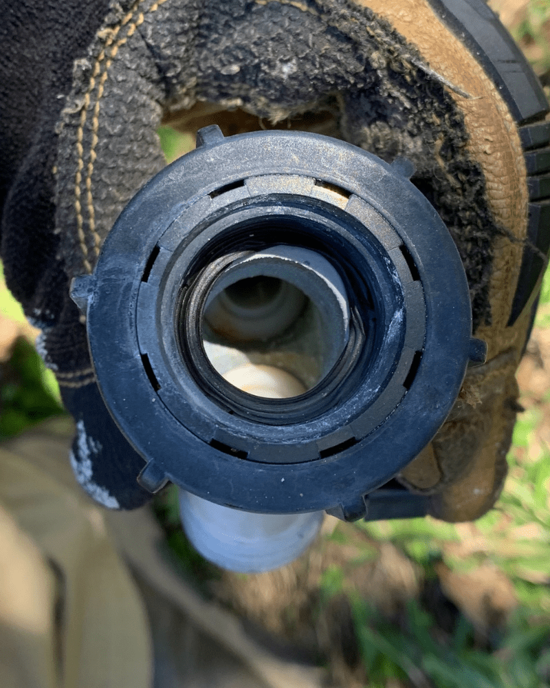 Photo is of the underside of a hose splitter. Inside the inlet is a deformed black hose washer. 