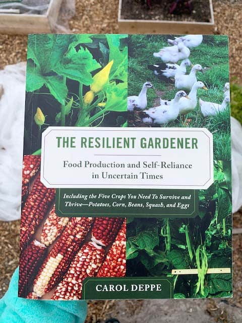 A hand holding book "the resilient gardener"