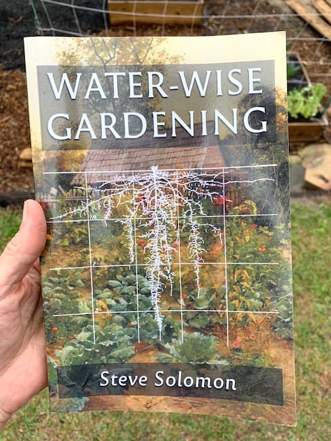 A hand holding the book Water-Wise Gardening by Steve Solomon
