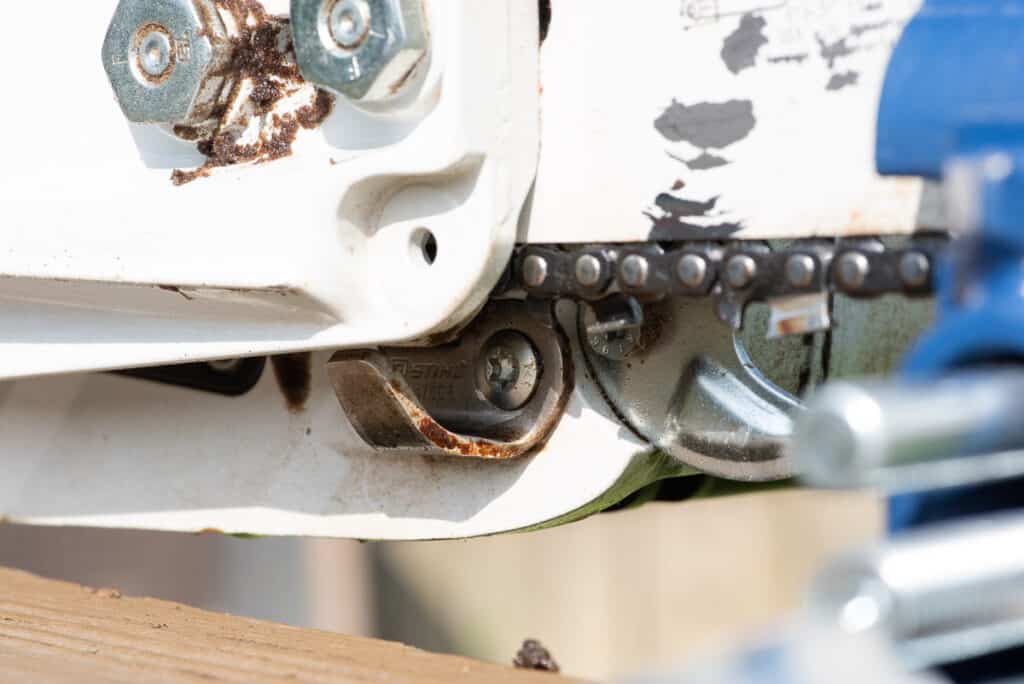Photo is of a close up of the sacrificial chain stop beneath the guide bar of a chainsaw. 