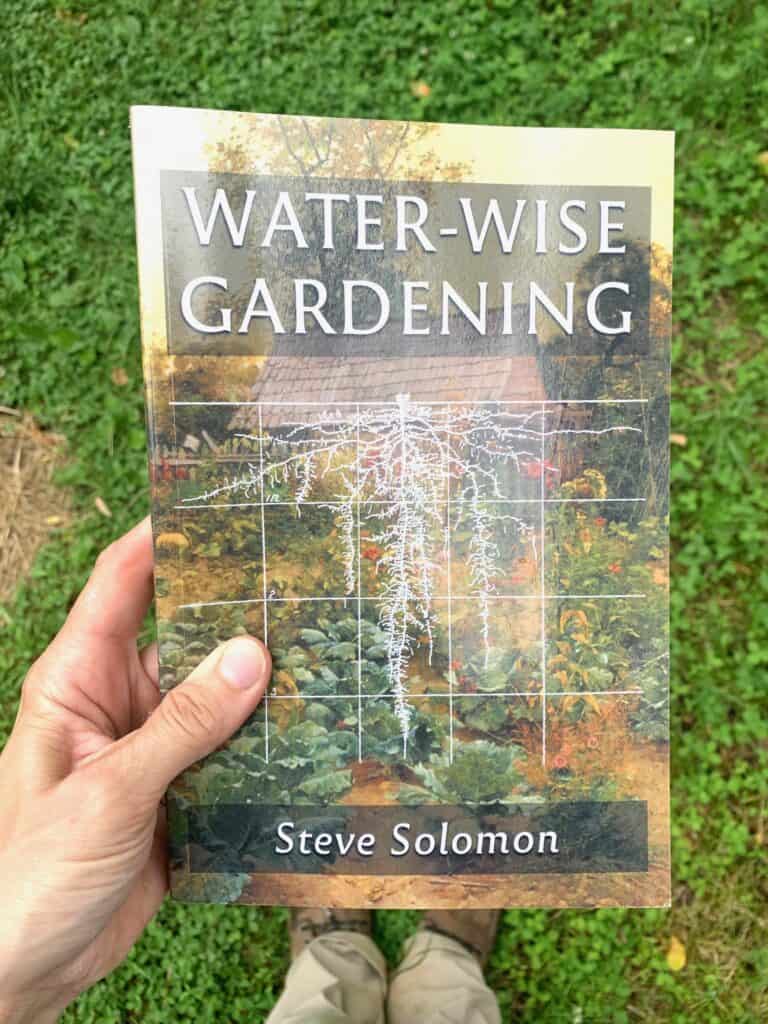 A hand holding the book Water Wise Gardening by Steve Solomon