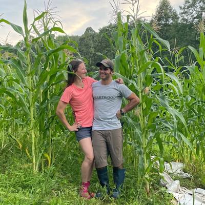 a man and a woman standing next to corn