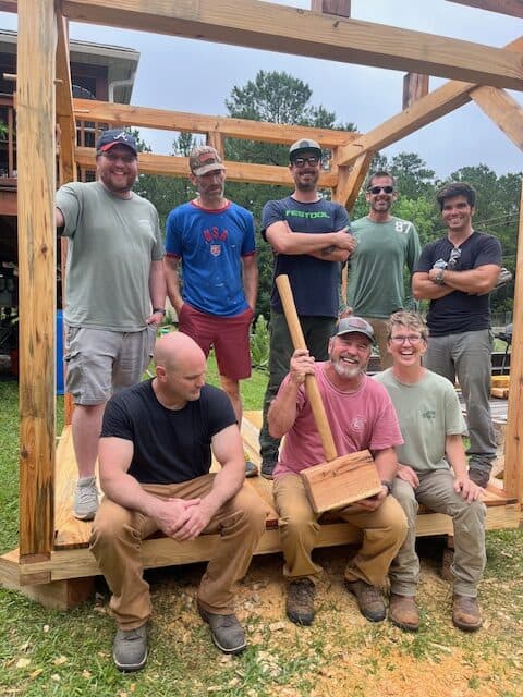 A group of people standing under a timber frame pergola