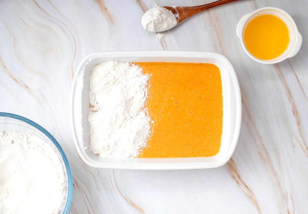 a baking dish with a pumpkin puree mixture partially covered with cake mix