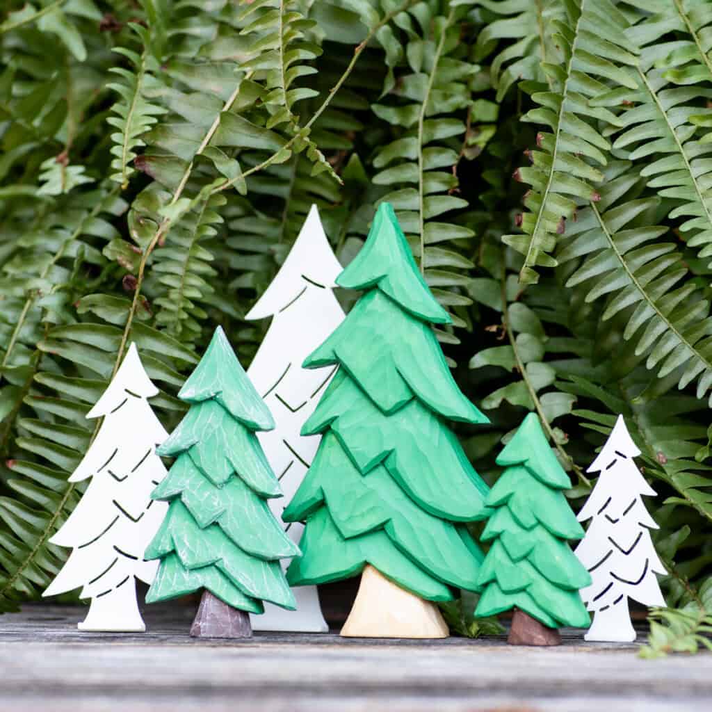 three wood carved Christmas trees of different sizes next to stencils