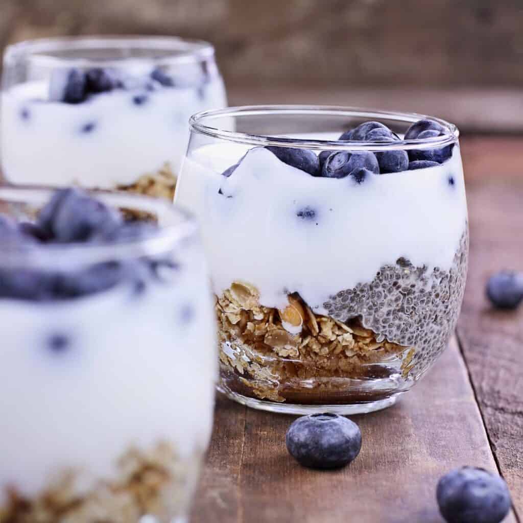 jars with yogurt, granola, chia seeds, and blueberries