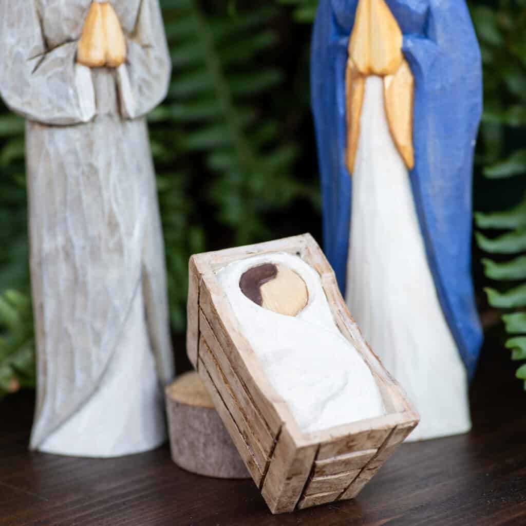 a photo of a wood carved three piece Nativity set with the focus on the manger