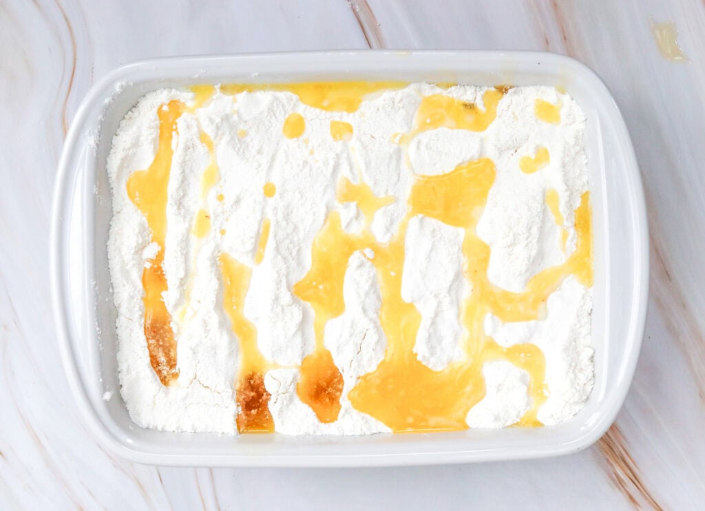 adding butter on top of a dump cake in a pan