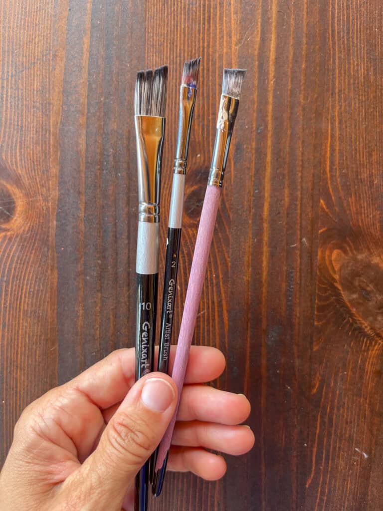 three flat paint brushes for painting miniatures