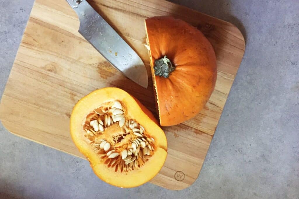 a cut in half pie pumkin on a cuting baord