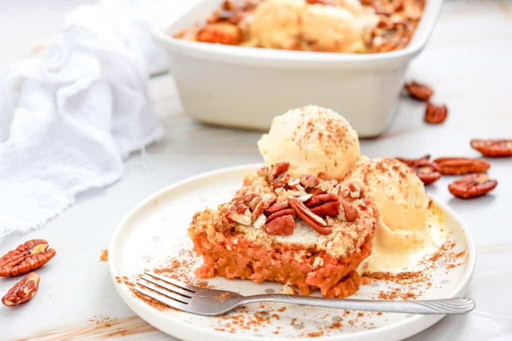 a piece of gluten free pumpkin dump cake with pecans and ice cream on top