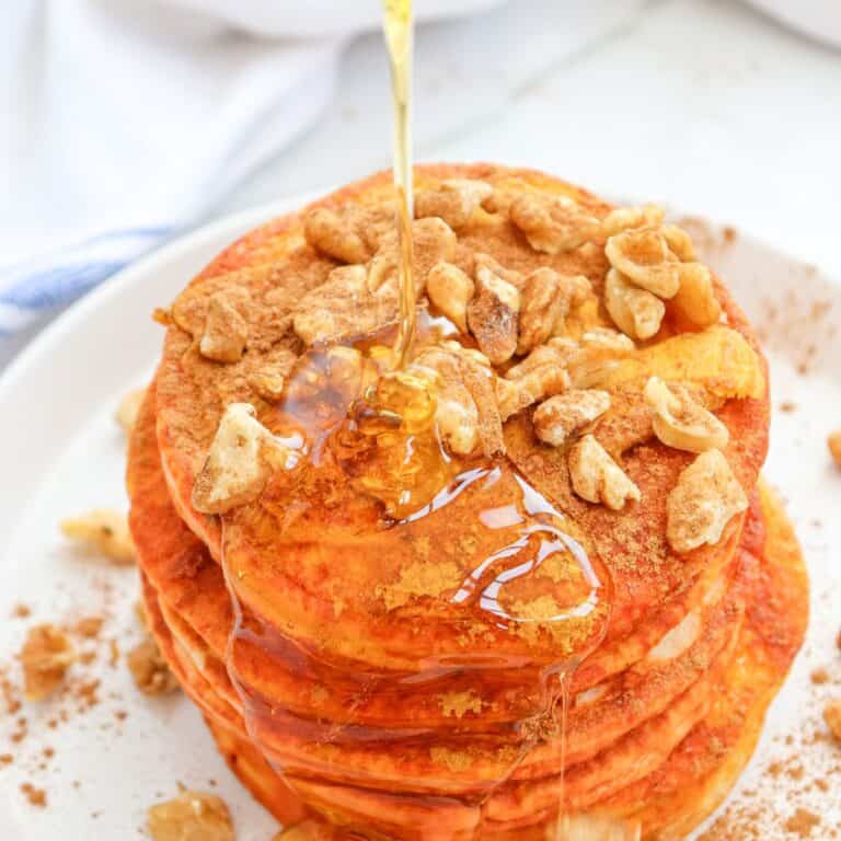 a stack of pumpkin pancakes with wanuts and maple syrup