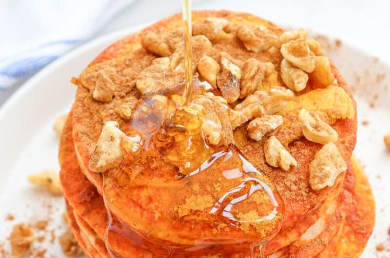 a stack of pumpkin pancakes with wanuts and maple syrup