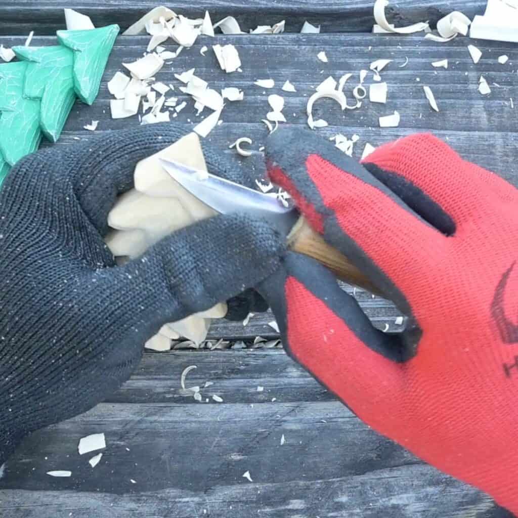 sloping the top of a wood carved christmas tree using a carving knife